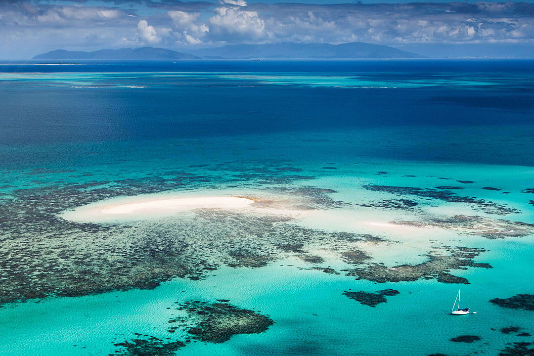 A boat sailing through the crystal-clear waters of the Great Barrier Reef, Australia.