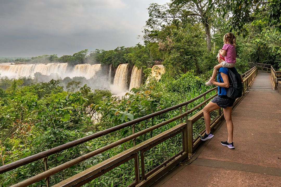 Mother and child enjoying the breathtaking view of Iguazu Falls from a scenic walkway in the rainforest