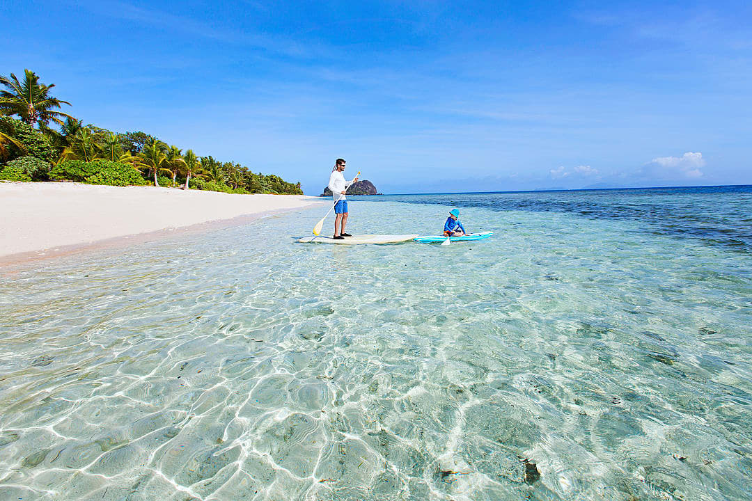 Father and son kayaking in clear waters of Fiji