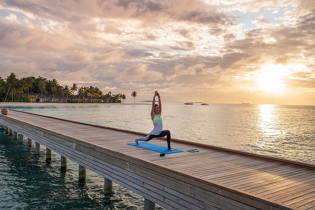 Sunrise yoga session on pier at Baglioni Resort, Maldives.