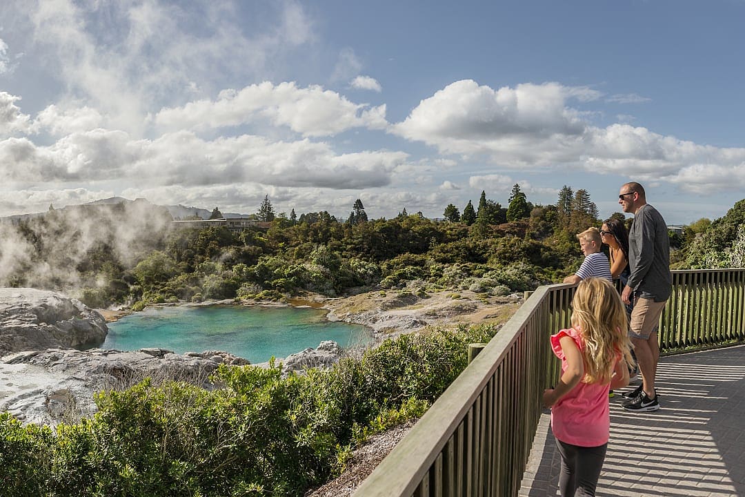 Family viewing the geothermal lake and geyser at Te Puia in Rotorua, New Zealand
