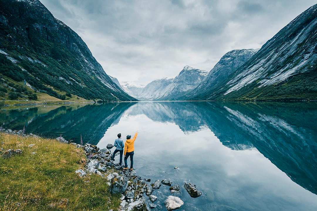 Two people standing by the still waters of the fjords in Norway.