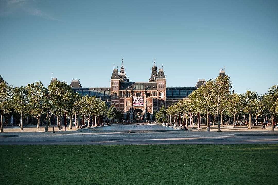 The grand brick and stone facade of the Rijksmuseum in Amsterdam seen from across the Museum Square.