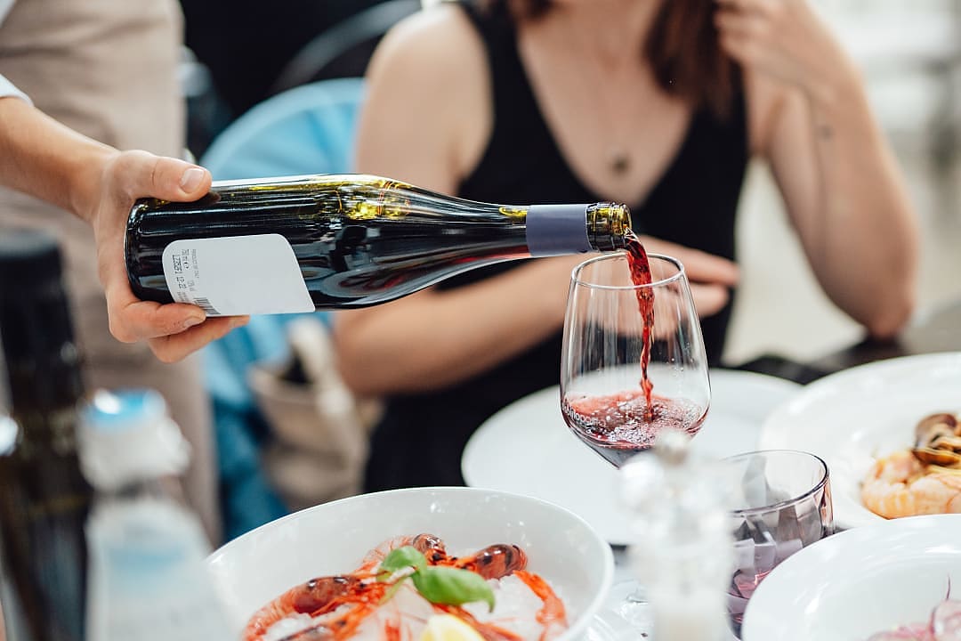A woman enjoying some red wine and a delicious meal in Italy.