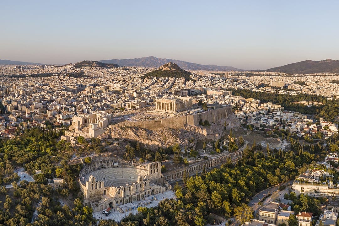 Aerial view of Athens at sunset with the Acropolis in the foreground.