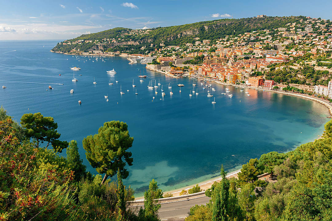 Picturesque bay of Villefranche-sur-Mer, France, with colorful buildings, yachts, and lush green hills
