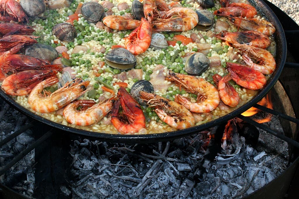 Spanish paella cooking over open fire.