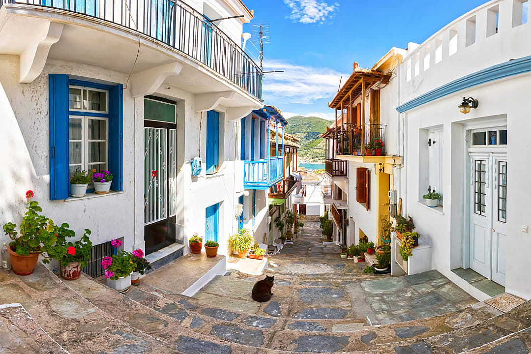 Alley between white-washed buildings with view to the sea in Skopelos, Greece
