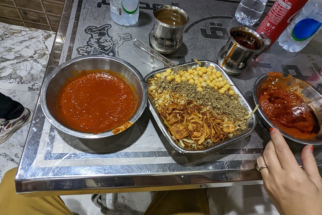 koshari, a bowl of lentils, rice, chickpeas, pasta, and tomato sauce topped with crispy onions