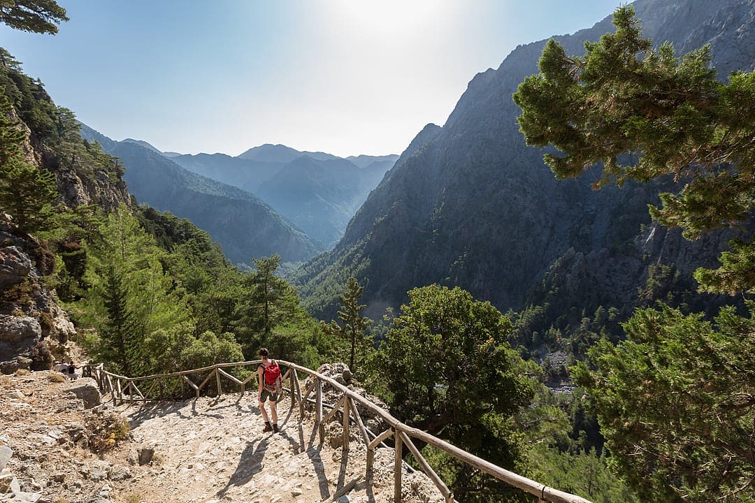 A lone hiker treks through Samaria Gorge’s breathtaking mountain landscape.