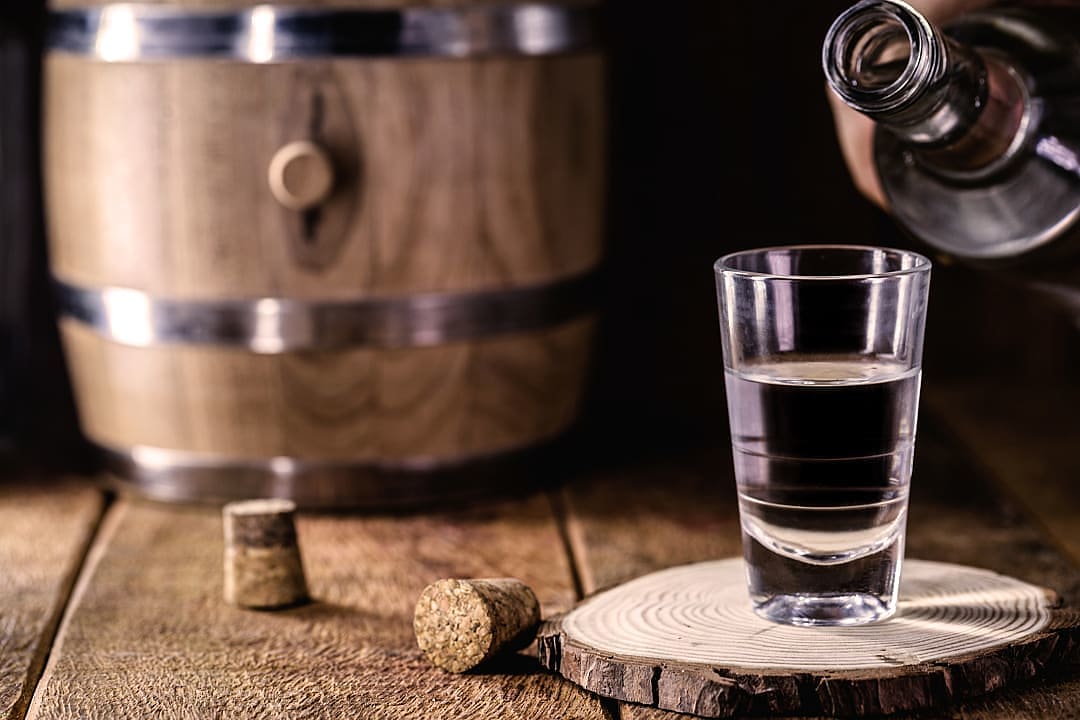 Spirit being poured in a shot glass, in a distillery.