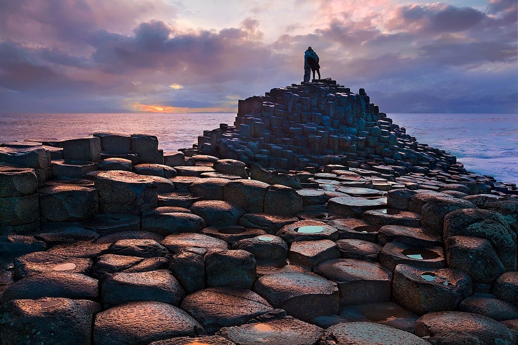 Couple watching the sunset at Giant's Causeway in Northern Ireland