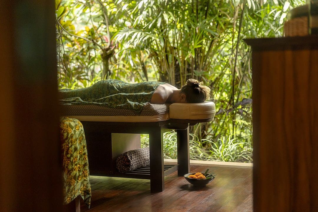 Woman receiving a relaxing outdoor spa treatment surrounded by lush greenery in Bali, Indonesia.