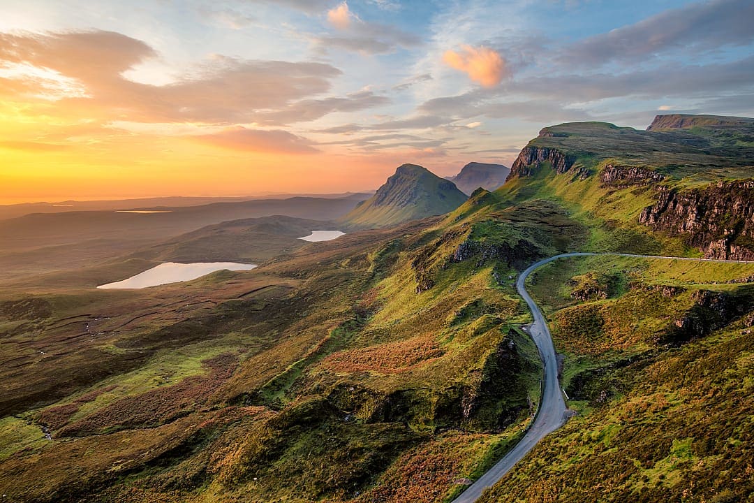 Orange clouds drift dramatically over rugged cliffs.