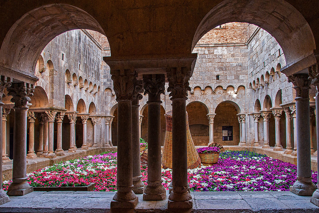 Historic courtyard with colorful flowers at The Flower Festival in Girona, Spain, showcasing floral art.