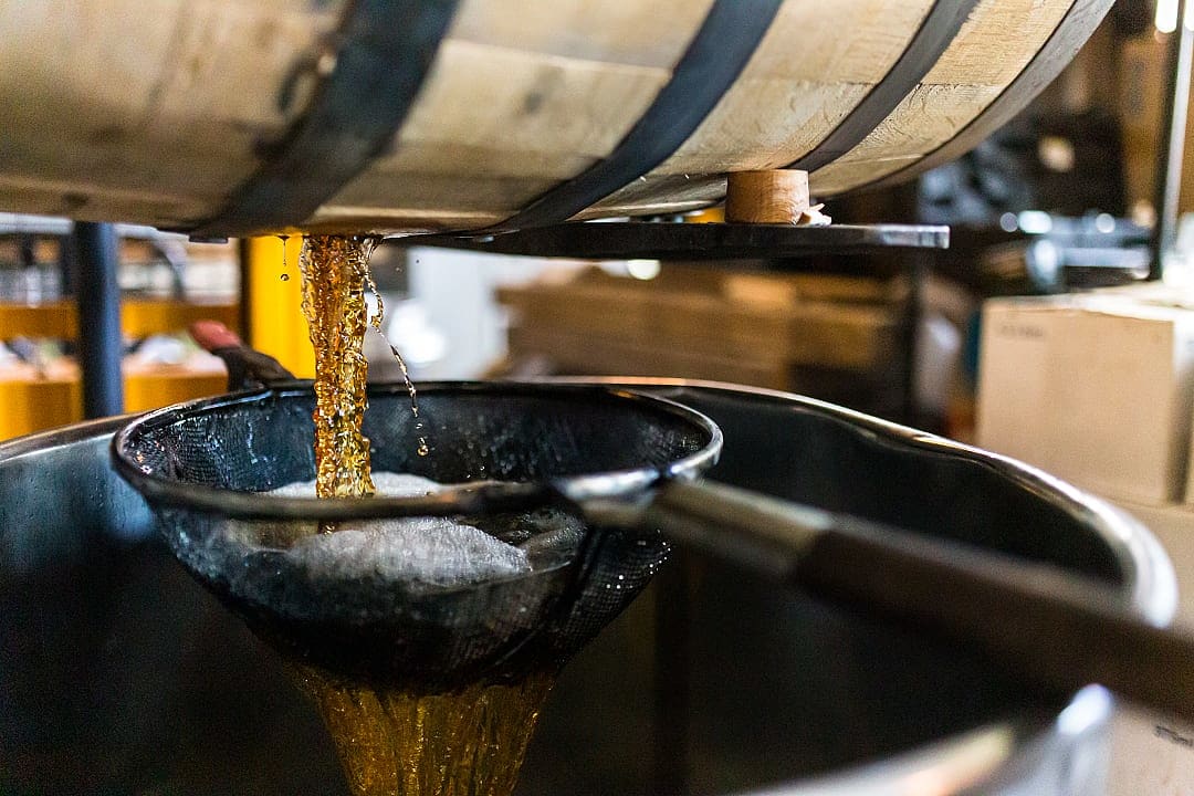 Whiskey poured from a barrel into a tank, Ireland.