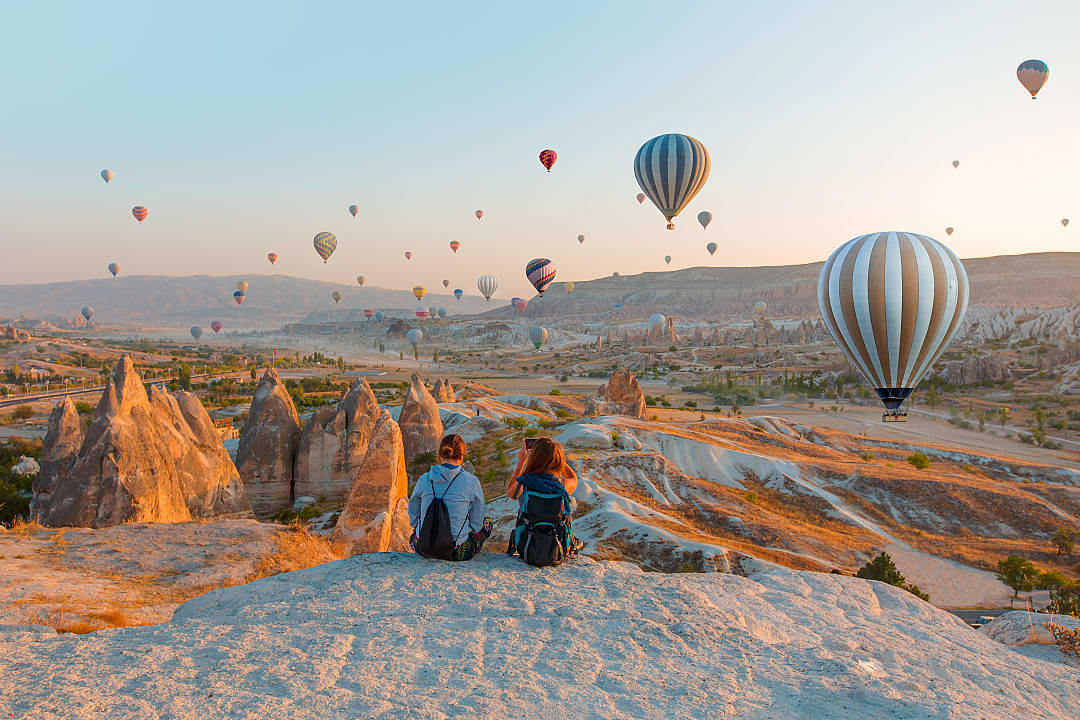 Mother and daughter watching hot air balloons flying over the rock landscape of Cappadocia, Turkey