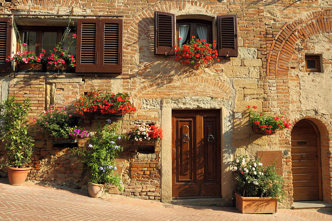 Tuscan farm like home, adorned with red flowers.