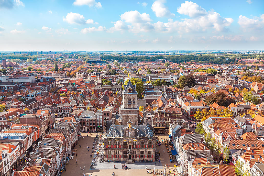 Aerial view of the historic Delft market square with the New Church tower and traditional gabled houses.