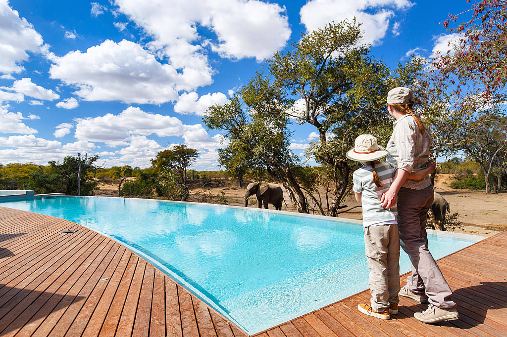 Mother and daughter watching elephants while at the pool of a luxury lodge