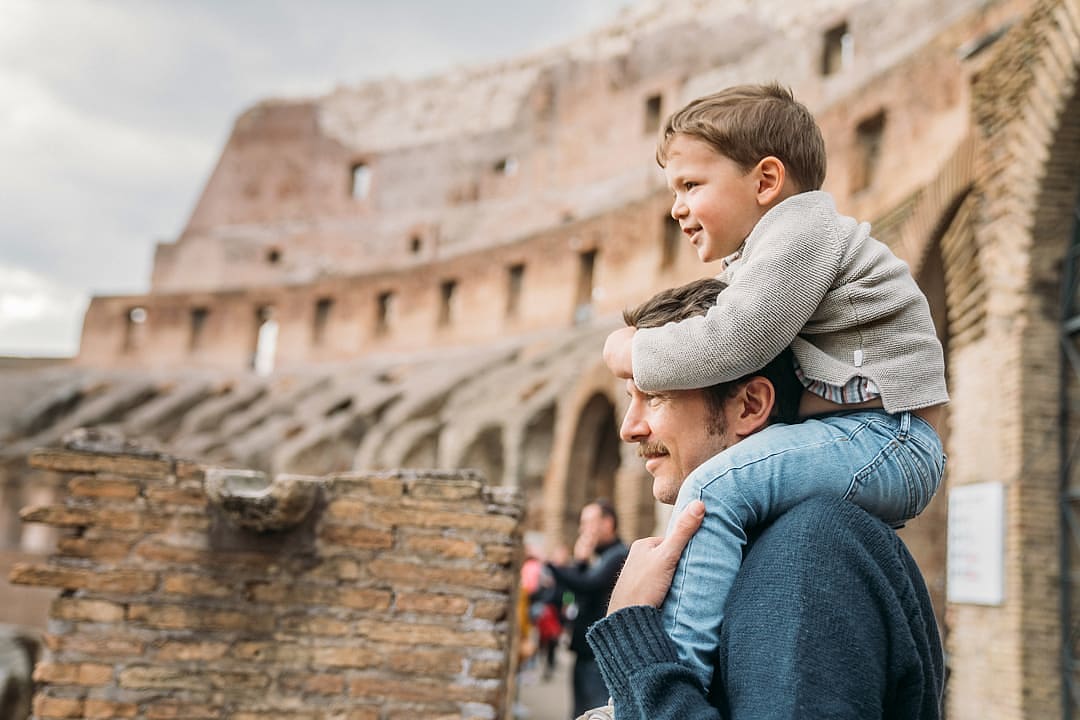 A father and son explore the historic Colosseum in Rome together.