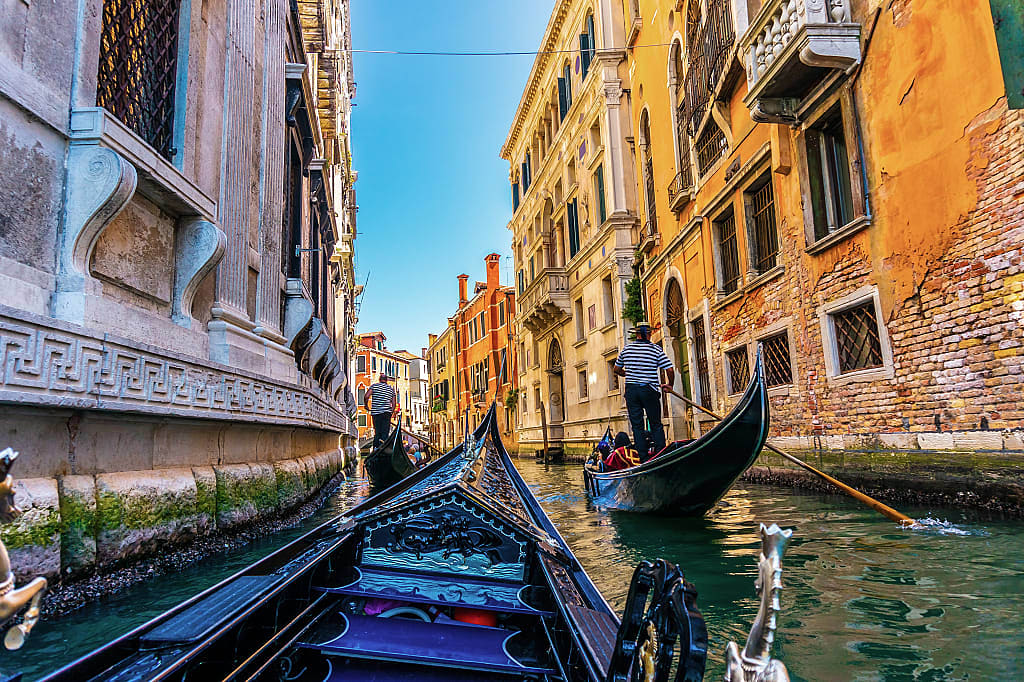 Gondoliers in sun filled canal in Venice, Italy,