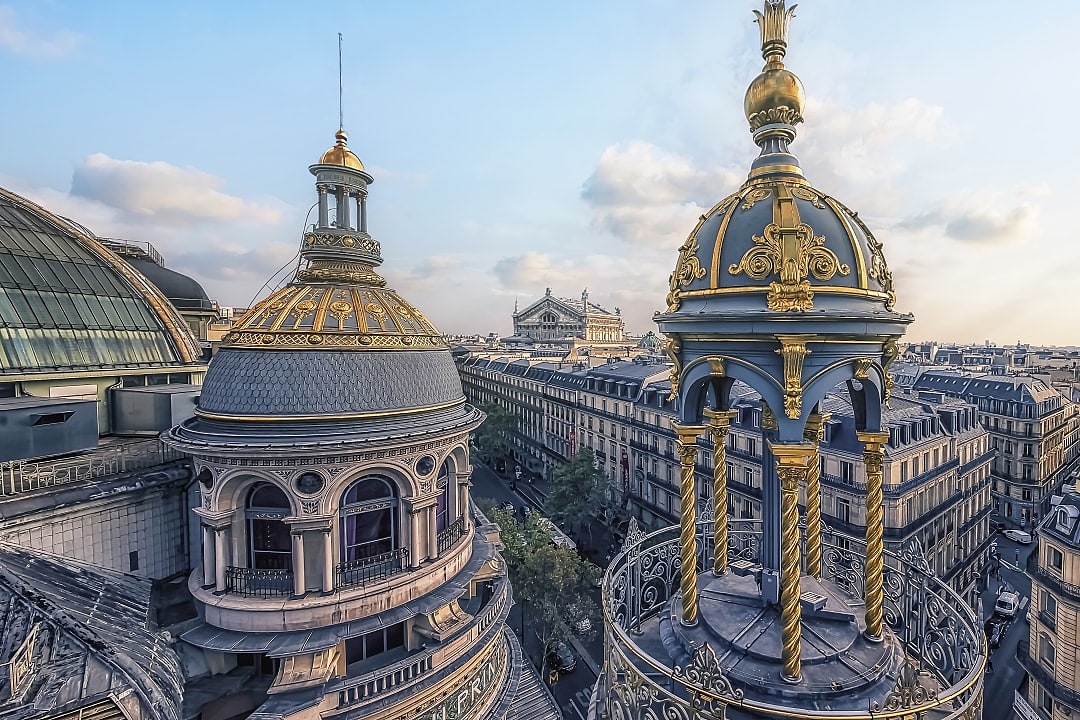 Golden rooftop domes of Galeries Lafayette overlook beautiful Parisian streets below.