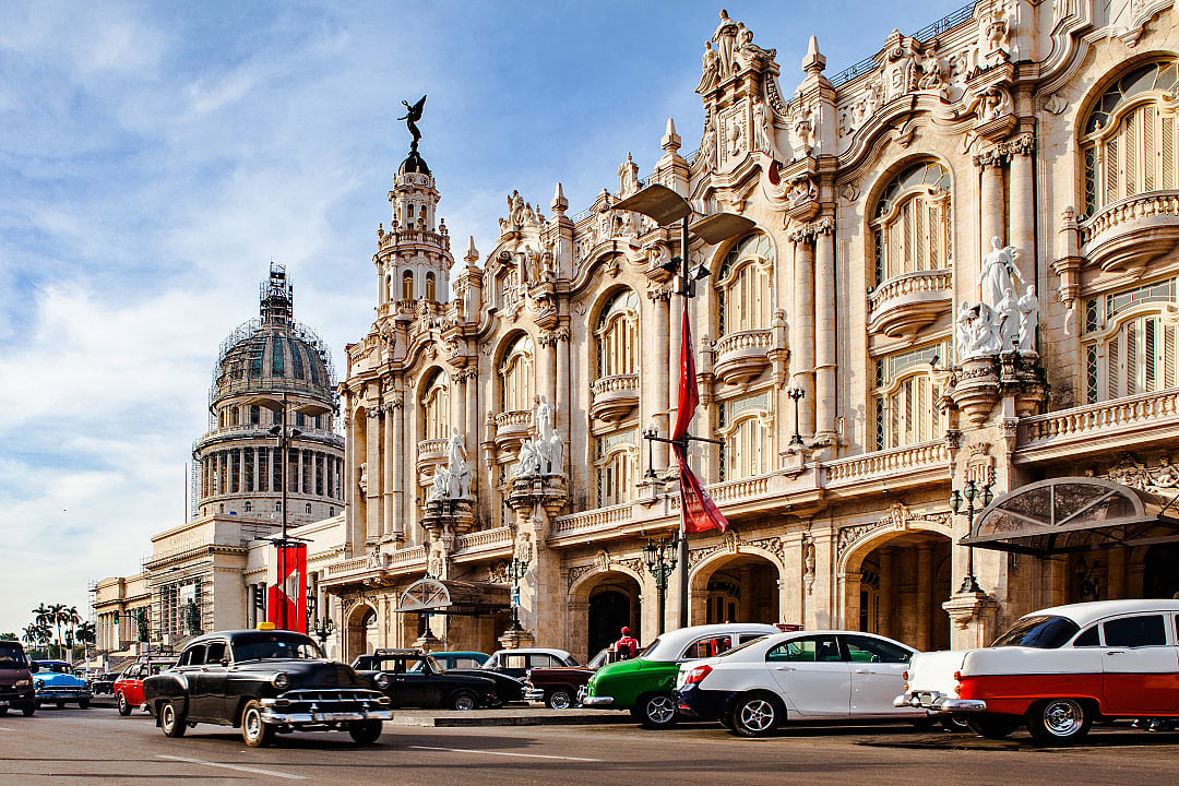 Classic car passing by The National Theatre in Havana, Cuba.