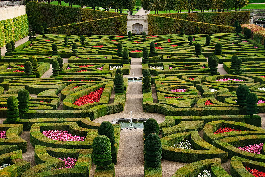 Formal gardens in the Loire Valley, France, featuring meticulously manicured hedges, vibrant flowerbeds, and elegant pathways
