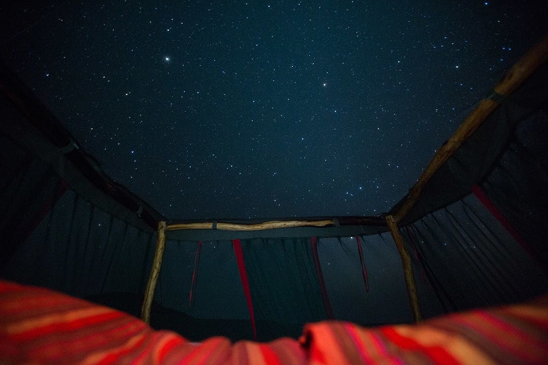 Starry night sky view from Elewana Loisaba Star Beds in Kenya, inside an open-roof luxury tent.