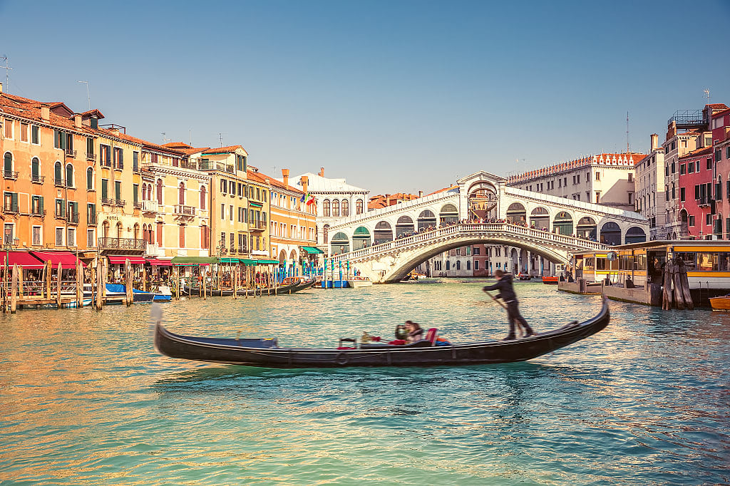 Couple riding in gondola near Rialto bridge in Venice, Italy
