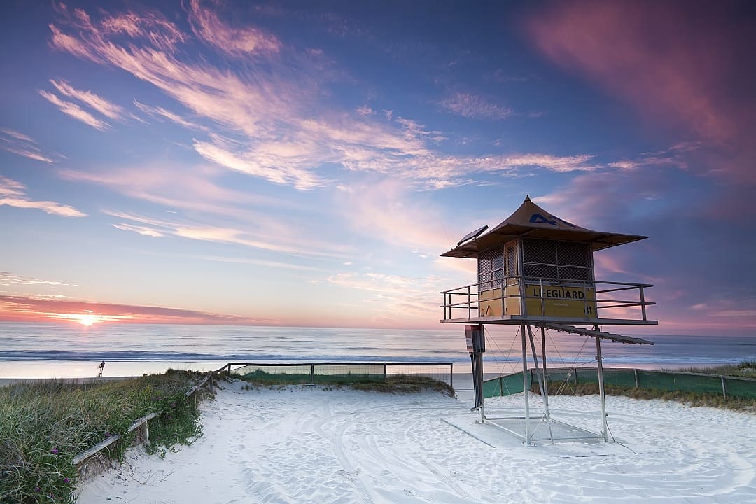 Lifeguard tower on sandy beach at sunrise