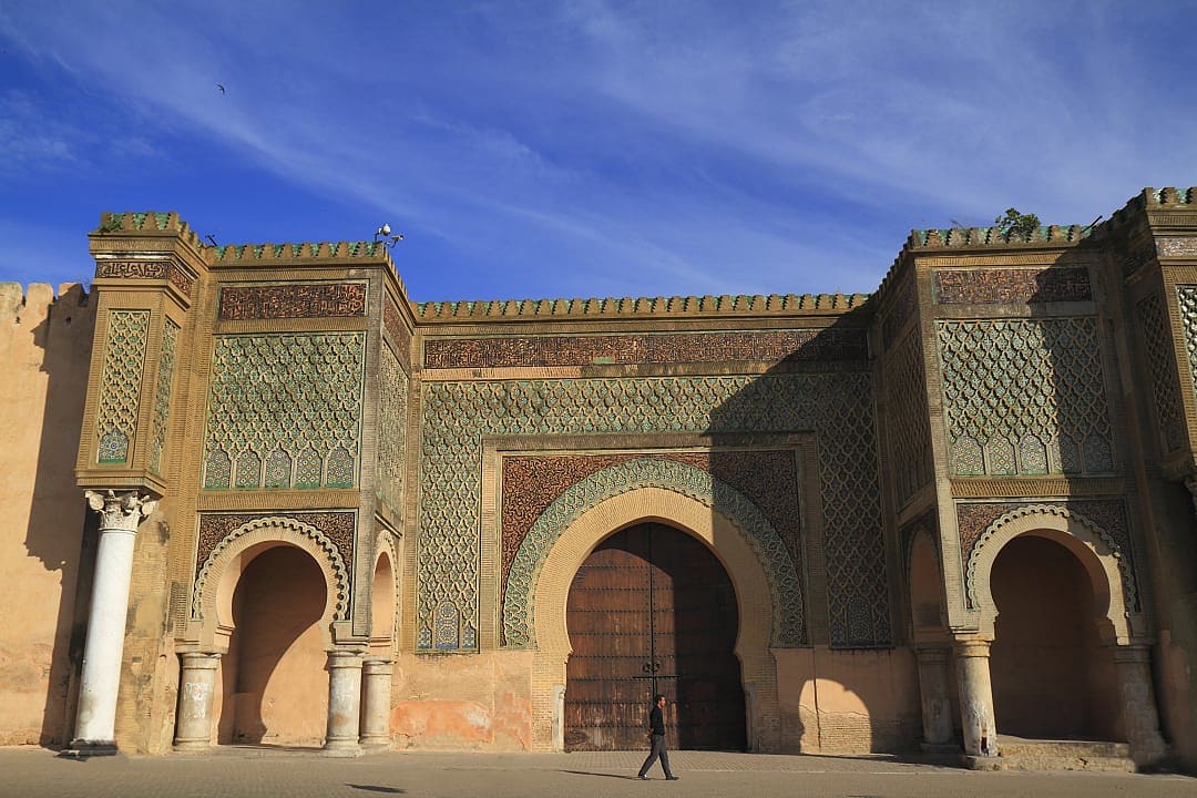 Man walking in front of the Bab Mansour Gate in Menkes, Morocco