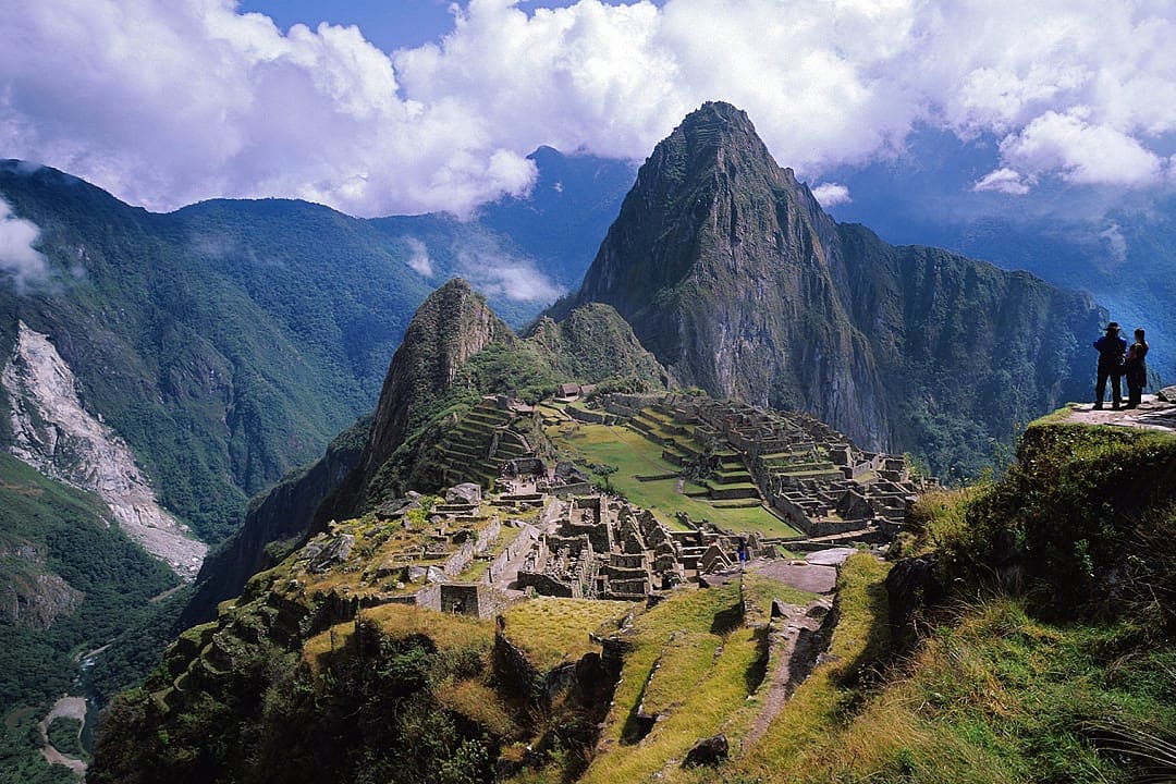 Panoramic view of the iconic Machu Picchu ruins surrounded by lush mountains in the Peruvian Andes.