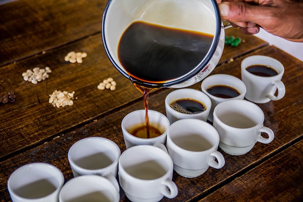 Coffee being poured into small white cups for tasting in Colombia