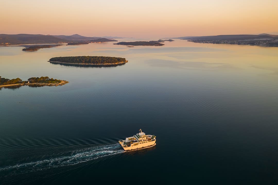 A ferry glides through Dalmatia’s calm waters, surrounded by stunning islands. 