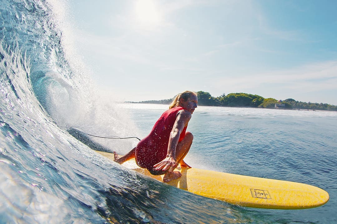 Surfer rides crystal-clear wave near tropical shores in the Maldives.