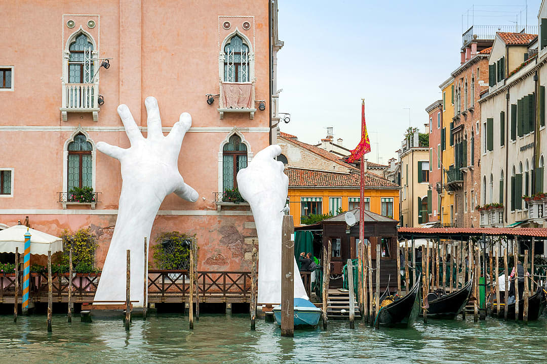 Art installation of giant hands emerging from a canal to support a building in Venice, Italy