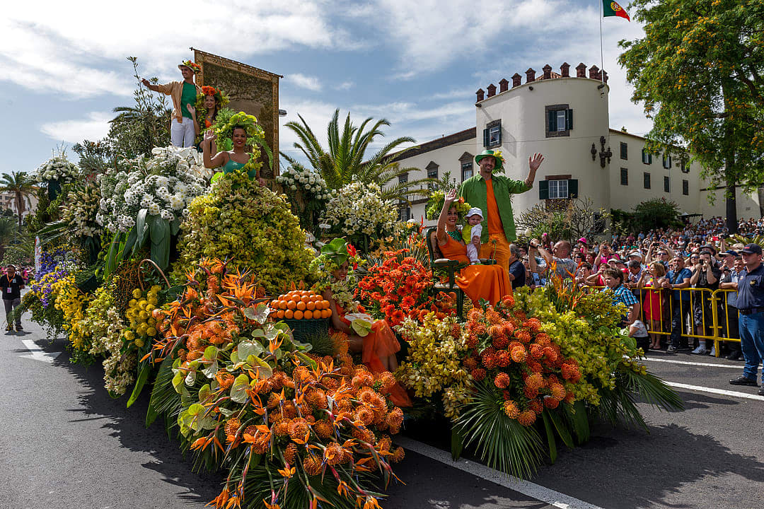 Vibrant floral float at Madeira Flower Festival in Madeira, Portugal, with performers and colorful blooms