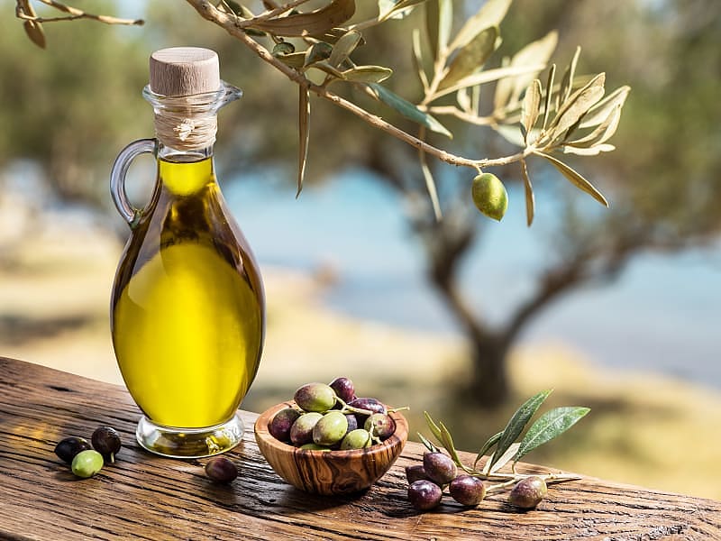 Olive oil and olives on a wooden table in an olive grove.