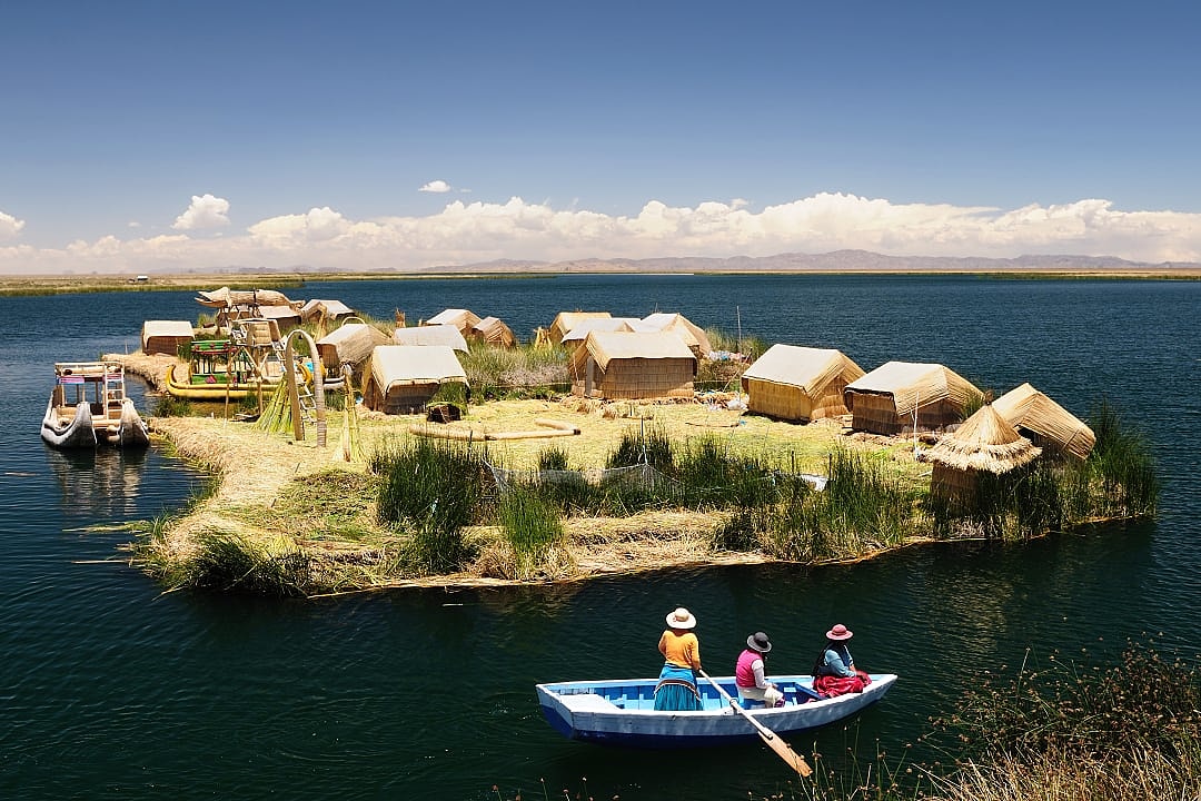 Uros floating island with boaters on Lake Titicaca, Peru