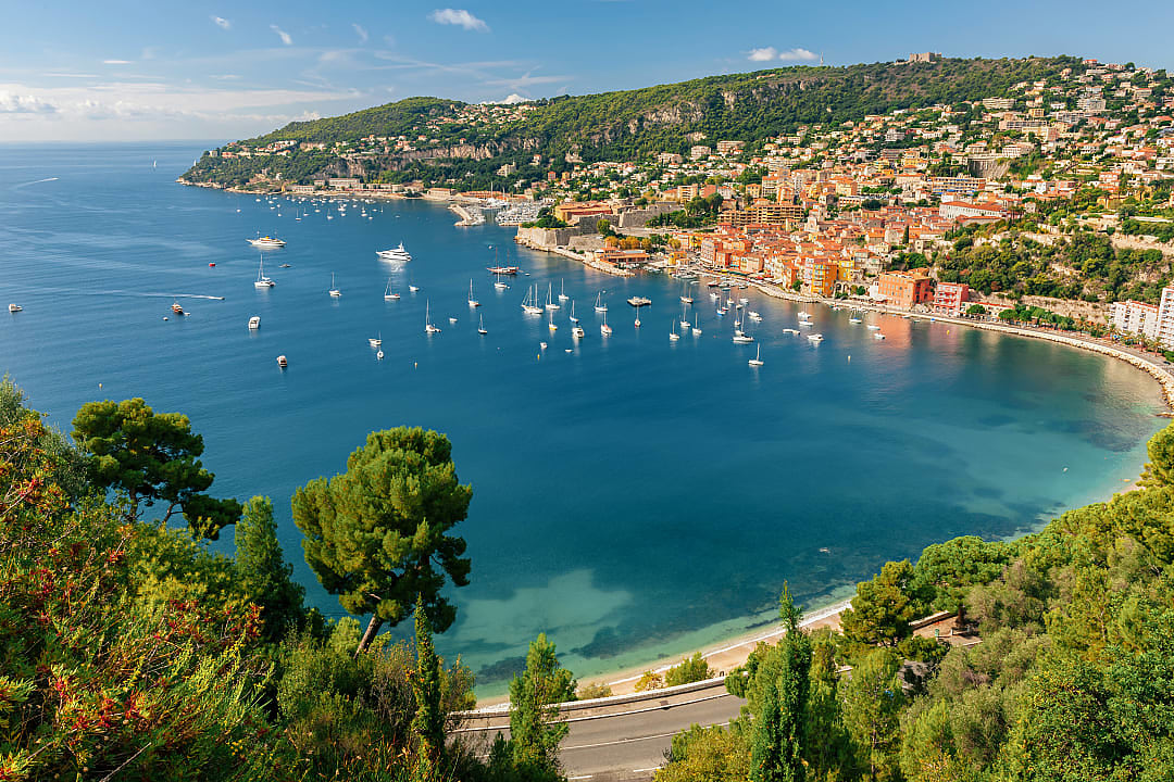 Picturesque bay of Villefranche-sur-Mer, France, with colorful buildings, yachts, and lush green hills