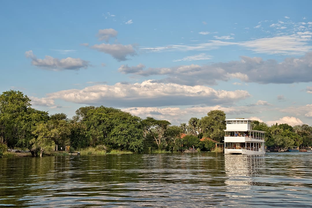 A river cruise boat glides peacefully through Zimbabwe’s scenic waters.