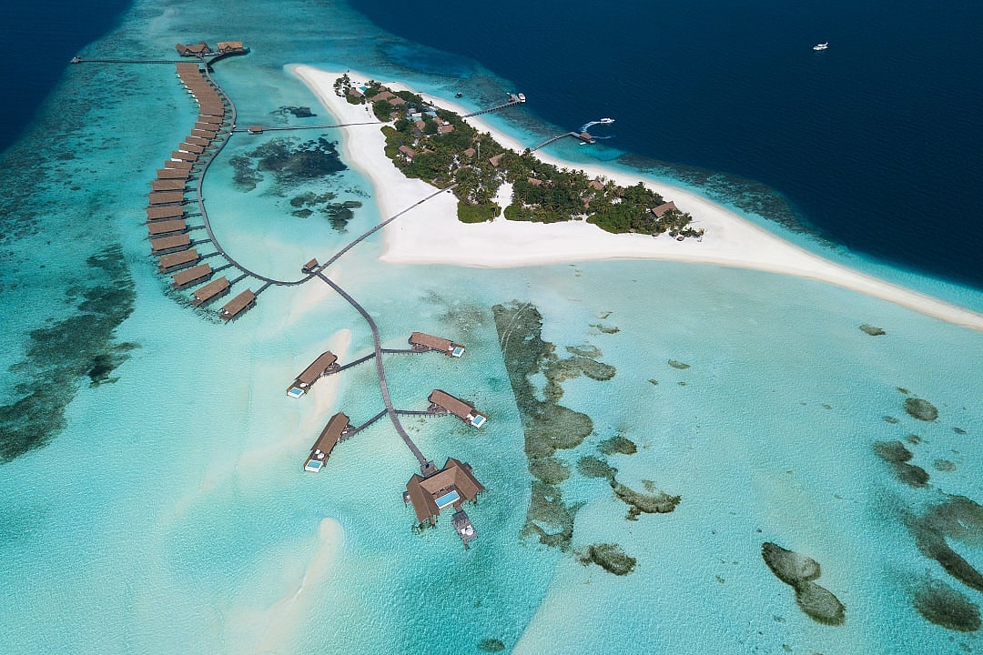 Overwater villas stretch across turquoise waters on Cocoa Island paradise.