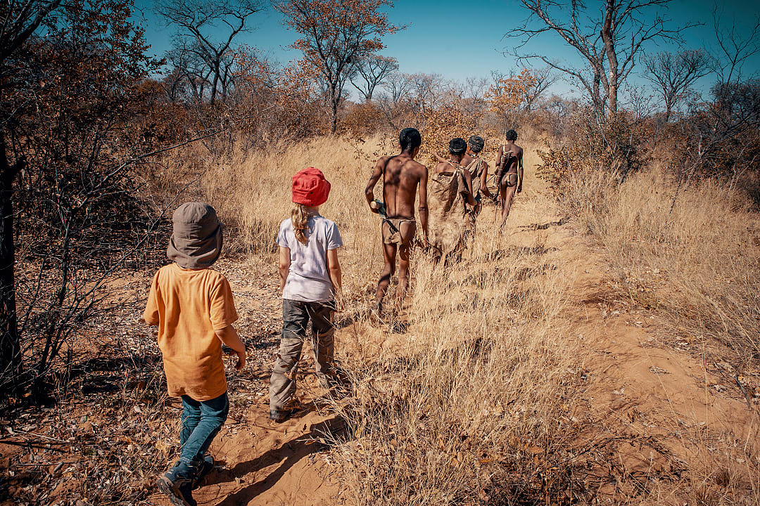 A group of people walking together through dry grassland, symbolizing shared discovery and connection during a journey in nature.