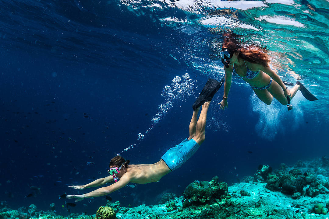 Couple snorkels through crystal-clear Maldivian waters, discovering vibrant marine life.