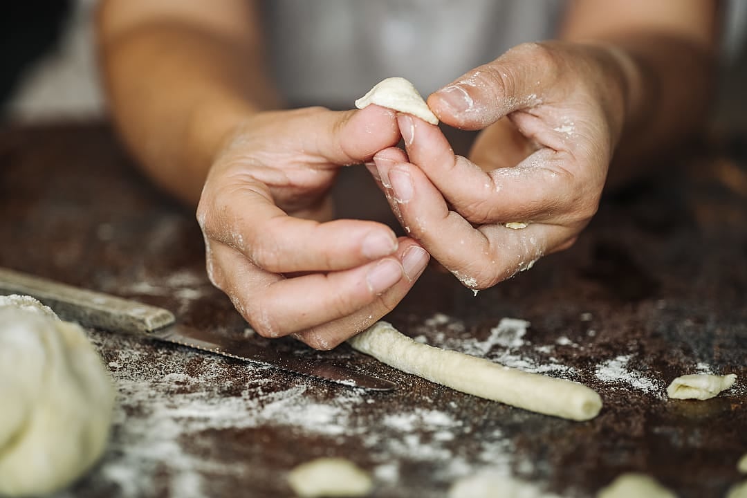 Skilled hands shape fresh pasta dough during an Italian cooking class.