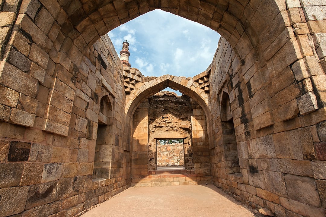 Ancient stone archway leading into historic qutub complex corridor