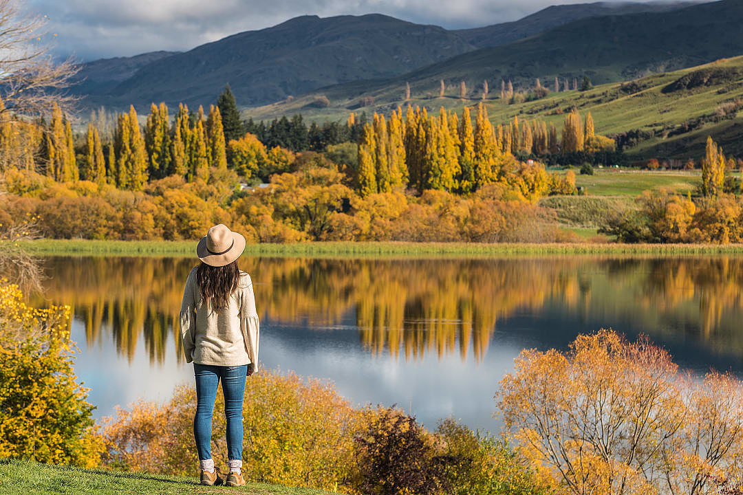 Woman staring lake wakatipu and the autumn landscape in Queenstown, new zealand