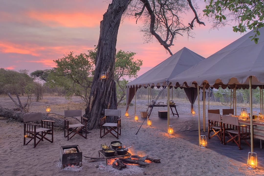 A luxurious safari camp glows beautifully under a stunning Botswana sunset.